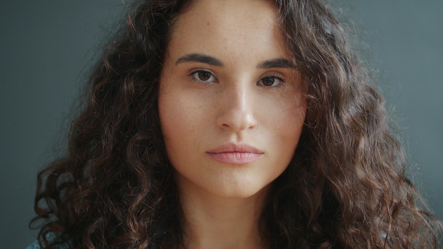 Retrato de mulher de cabelo cacheado olhando pra câmera